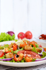 Light tasty salad with meat of a cancer, shrimps, lettuce, garlic croutons, tomatoes, red onions on a white background. Free space for an inscription.