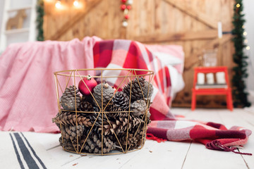 Christmas decorations in basket and pine cones on floor close up.