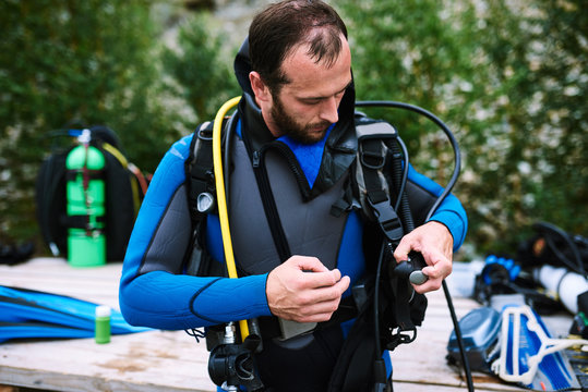 Male diver in wetsuit checking equipments before immerse