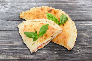 One whole and half of cooked calzone on wooden surface
