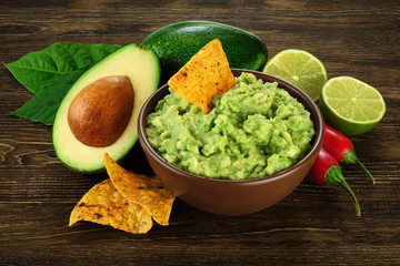 Guacamole nachos and guacamole ingredients on dark wooden background. - obrazy, fototapety, plakaty