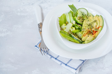 Green salad with broccoli, sprouts and avocado, light background