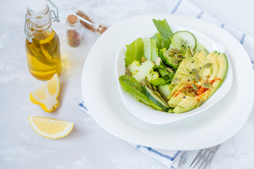 Green salad with broccoli, sprouts and avocado, light background