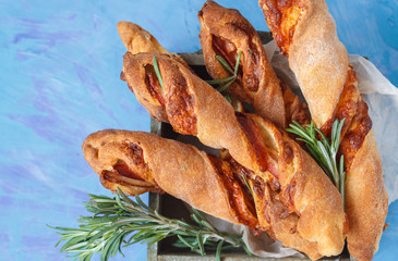 Tasty cheese sticks with bacon, herbs in wooden box.