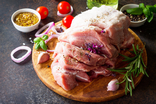 Pork fillet on a cutting board, raw meat, assorted minced pork and beef and various spices on a stone or slate background. Copy space.