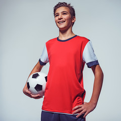 smiling teen boy in sportswear holding soccer ball