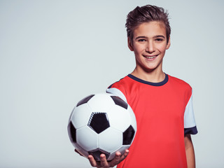 smiling teen boy in sportswear holding soccer ball