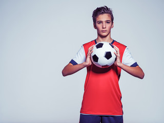 Photo of teen boy in sportswear holding soccer ball