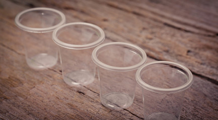 Empty clear color plastic cup on Top wooden table with detailed textured look clean, soft and warm , use as background for product display.