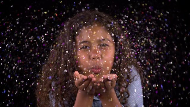Cute girl blows glitter at the camera.