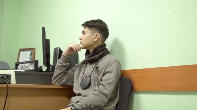 Hearing aid setting. Center of hearing aid for the selection and adjustment of the hearing aid. A person with hearing loss at a doctor's appointment.