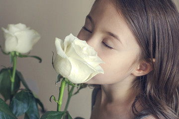 Six-year old girl with closed eyes enjoying the scent of white roses