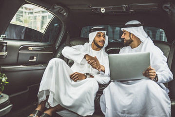 Two arabian businessmen talking about business in the company limousine - obrazy, fototapety, plakaty