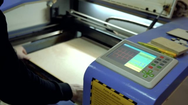 CNC engrave. Laser engraving on wood. Worker monitors the CNC machine.