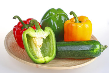 Green,red and yellow bell pepper with zucchini on wooden plate