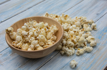 Popcorn in wood bowl on light blue wooden texture