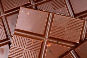 Chocolate bars as background. Milk and dark shiny chocolate texture. Stack chocolates pattern. Stunning beautiful cacao brown dessert sweets. Studio photo.
