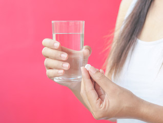 Woman hand with pills medicine tablets and glass of water in her hands. Healthcare, medical supplements concept