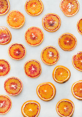 Fototapeta na wymiar Natural fruit pattern concept. Fresh juicy blood orange slices over light marble table background, top view