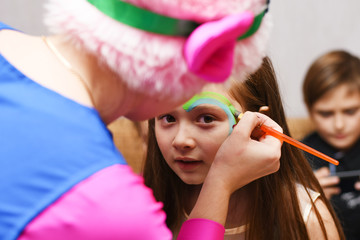 A beautiful girl paints an animator at a birthday party