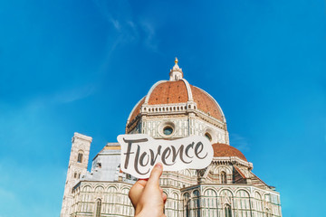 Hand written lettering card in girl's hand with word Florence in front of Florence duomo. Travel...