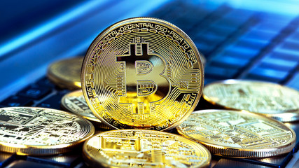 Photo Golden Bitcoins (new virtual money ) close-up on a blue background with a computer keyboard. 