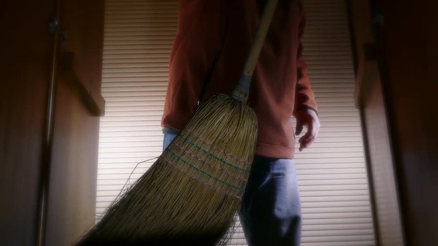 Person opening doors and placing a broom into a cupboard.