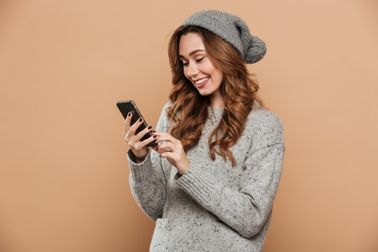 Close-up of gorgeous young woman in winter clothes chatting on mobile phone