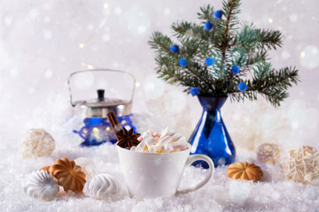Fototapeta na wymiar Cup of hot beverage with marshmallow and spices on snow background.