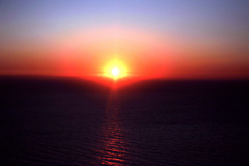 Fototapeta na wymiar The red sunset sky with the sun and clouds. Beautiful and colorful sunset sky. Oia Santorini Greece
