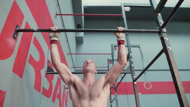  Low angle view of athletic man doing butterfly pull ups in a Crossfit gym.