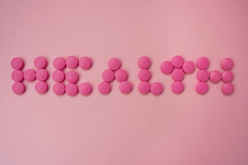 Pink pills on a pink background. The word 