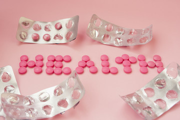 Pink pills on a pink background. The word "health" of pills and  empty blisters from tablets. Creative