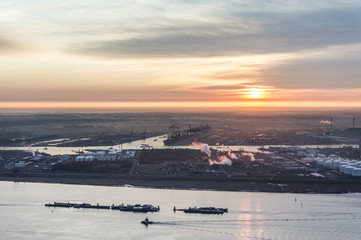 Sunrise over the Port of Antwerp with the Scheldt river and vessels in the foreground and the delwaide dock with the MSC terminal in the background
