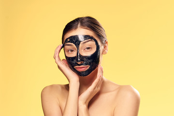 Black coal cosmetic face mask, woman on a yellow background, brunette, beauty, health