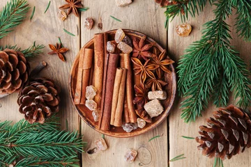 Fensteraufkleber Mixed christmas spices in plate on wooden rustic table top view. Anise star, cinnamon sticks and brown sugar. © juliasudnitskaya