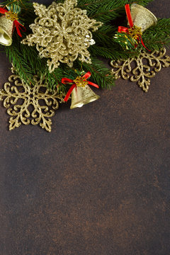 Christmas tree and decorative snowflakes, bells, ribbons on a brown background with space under the text.