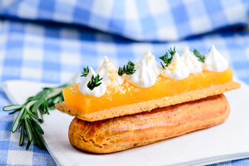 Traditional French dessert. Delicious eclair dessert with cream on tablecloth, selective focus