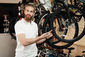 Fototapeta na wymiar A salesman in a bicycle shop poses near a bicycle.