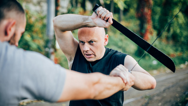 Martial arts instructor demonstrates machete fighting. Long knife weapon training