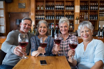 Group of smiling senior friends having red wine in restaurant