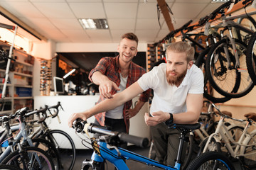 A seller at a bicycle store helps a young buyer choose a new mountain bike.