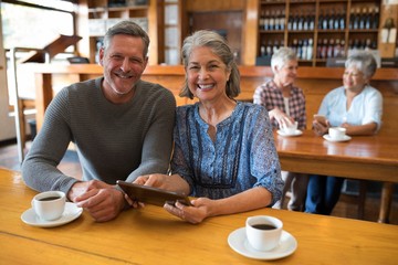 Smiling senior couple using digital tablet in restaurant
