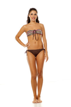 Young pretty brunette posing in bikini on white background