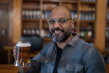 Smiling man having glass of beer in restaurant