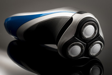 Closeup on electric shaver with circular close cut blades on dark shiny black and grey background