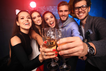 Enjoying amazing party. Group of beautiful young people dancing with champagne flutes and looking happy.