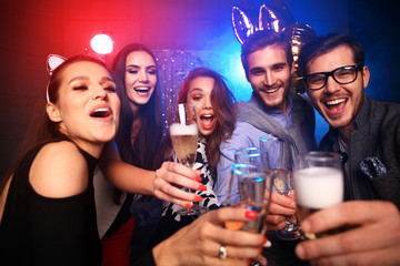 Enjoying amazing party. Group of beautiful young people dancing with champagne flutes and looking happy.