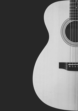 black and white acoustic guitar showing curve of body shape, isolated on black. music background
