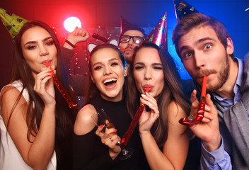 Friends making big party in the night. Five people throwing confetti and drinking champagne.